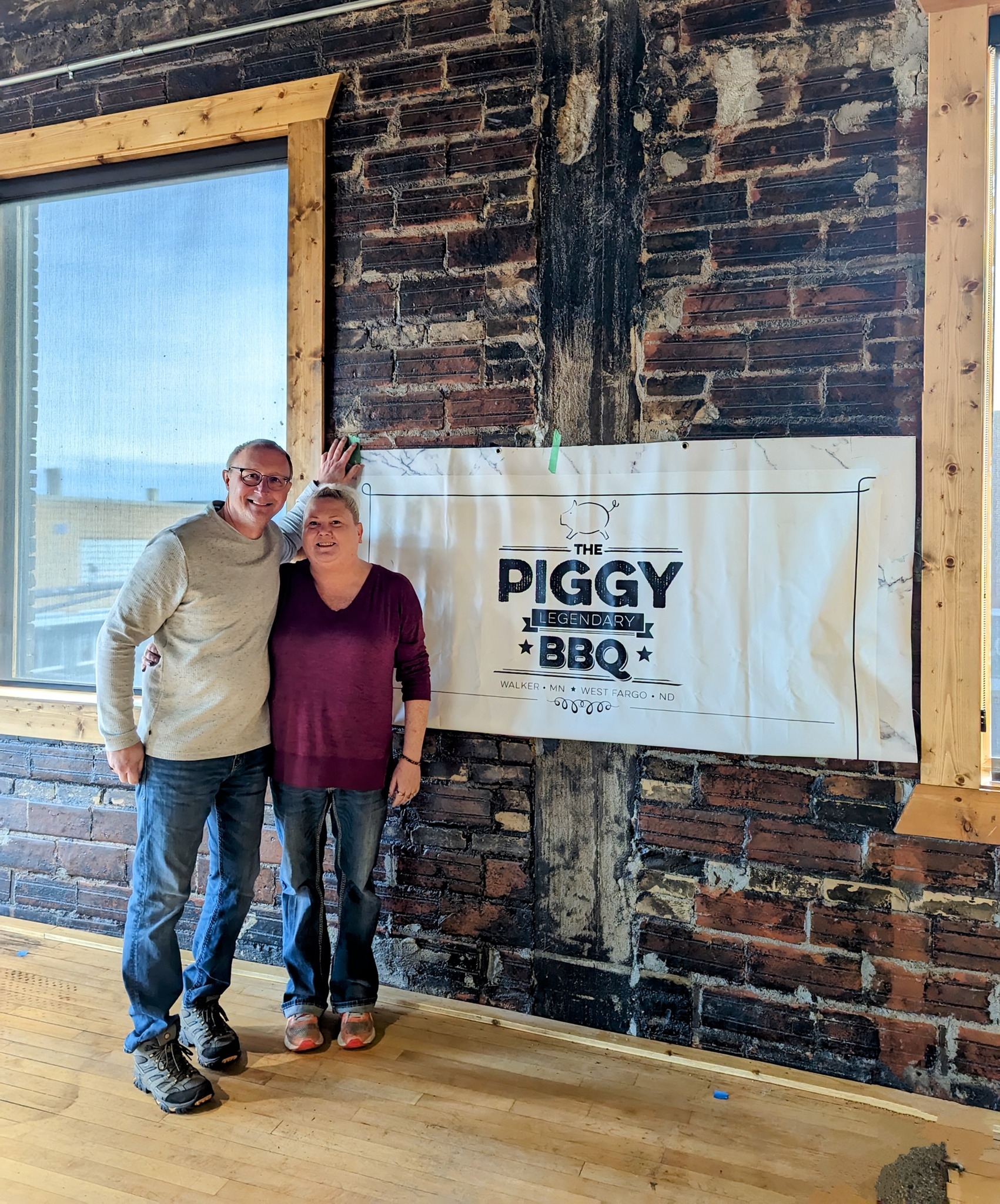 The Piggy BBQ of Thief River Falls' owners, smiling in front of sign
